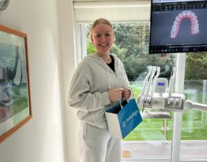 Happy patient holding aligner and Invisalign gift bag